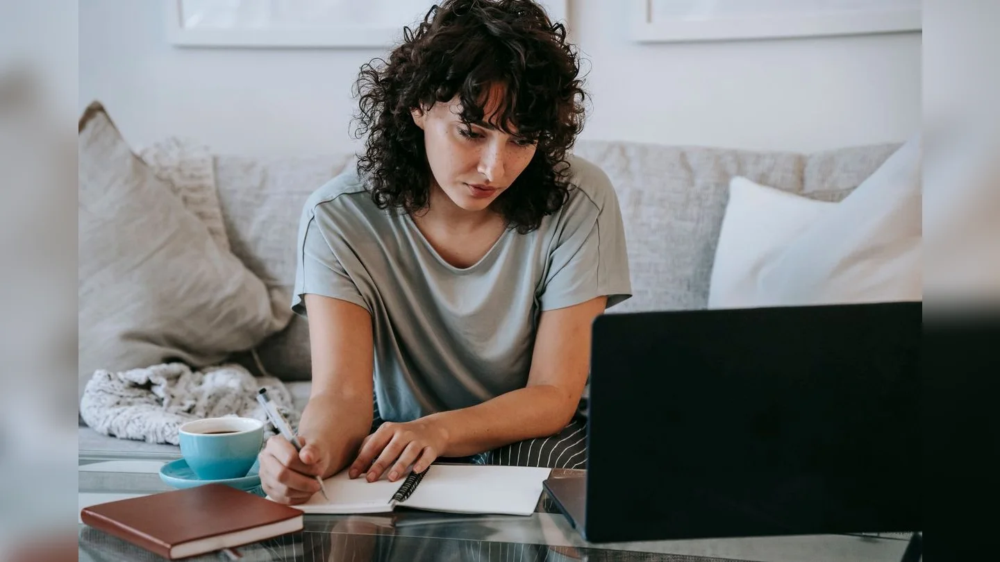 Person comparing information using a laptop and notebook