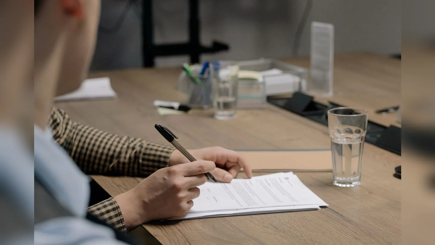 Hands reviewing and completing paperwork at a desk