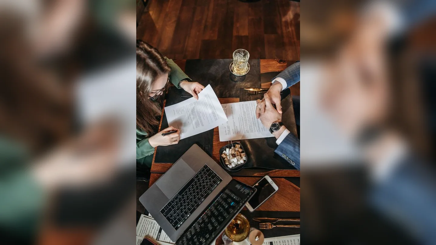 People reviewing documents beside a laptop