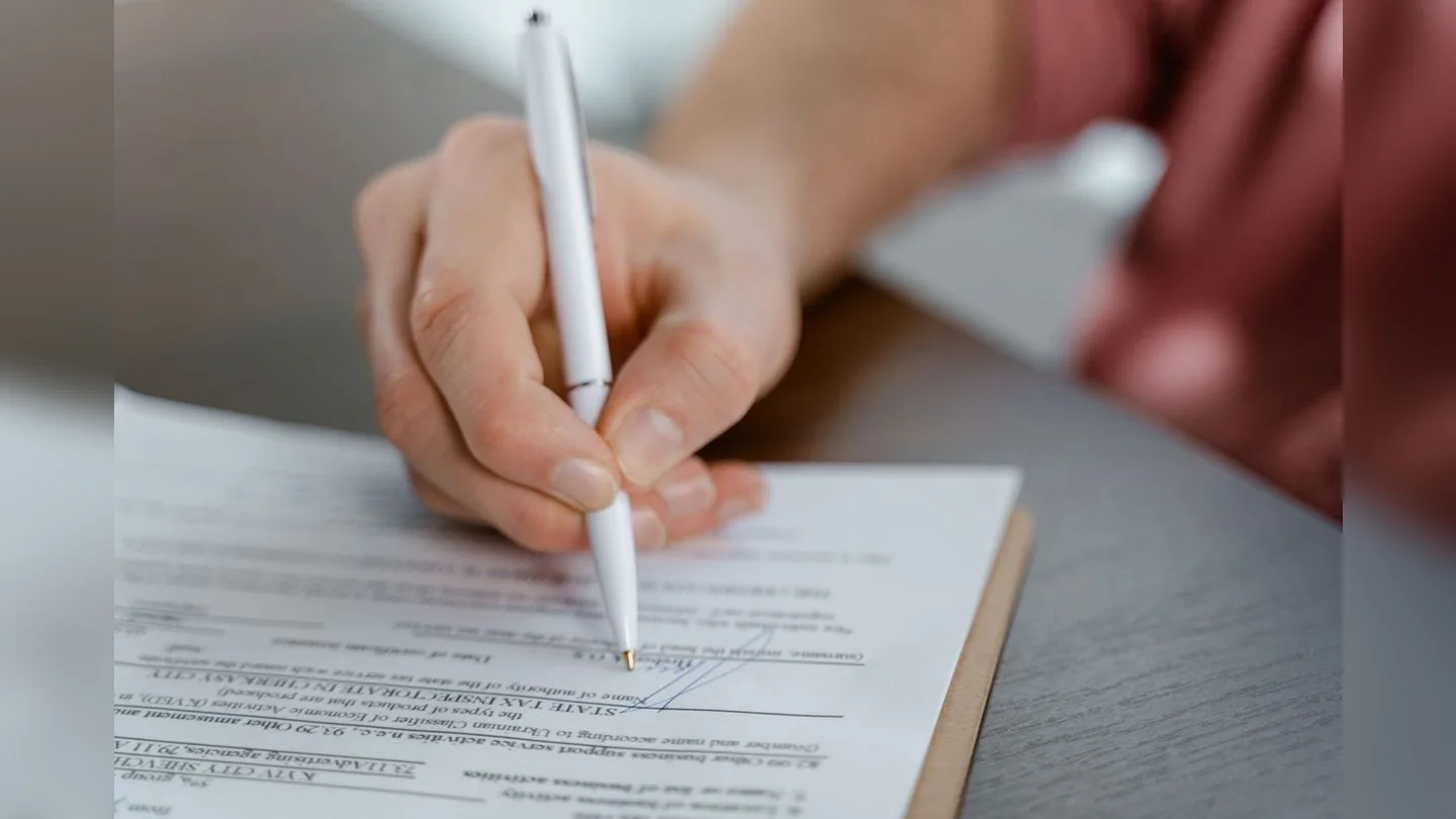 Hand completing a document with a pen