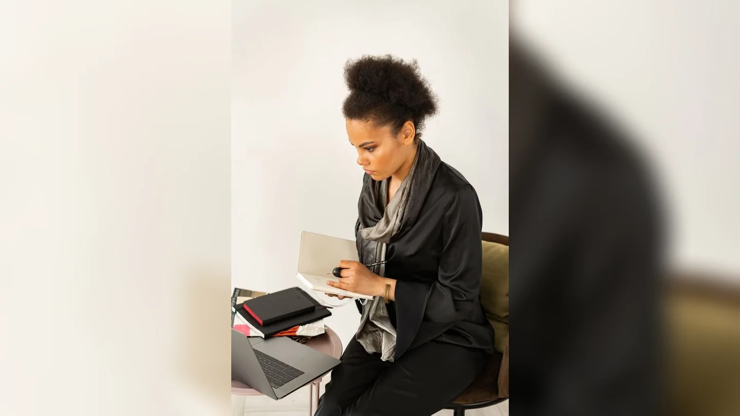 Person taking notes and reviewing information on a laptop