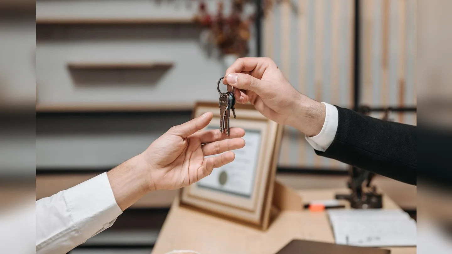 Hands exchanging keys across a desk