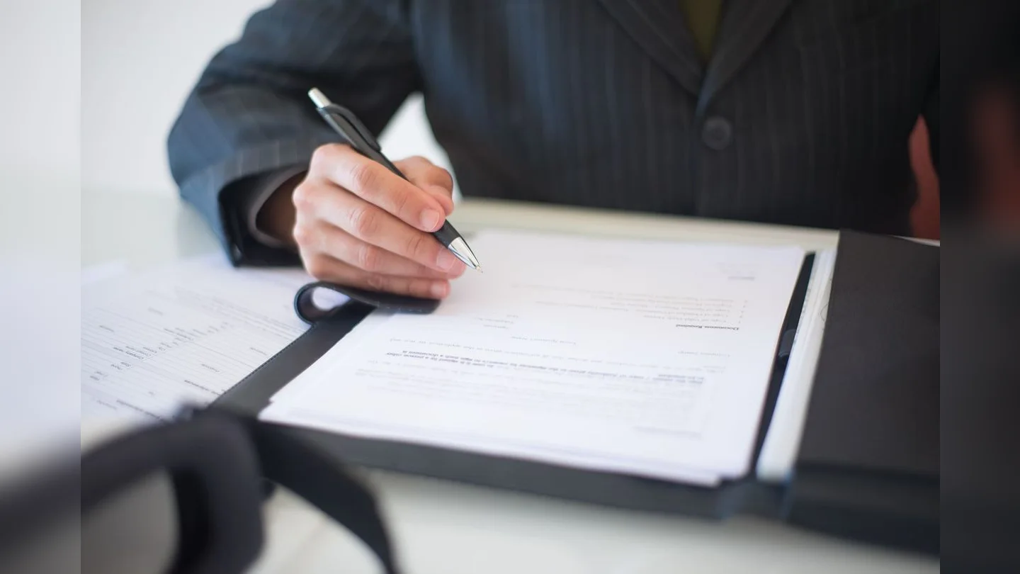 Hands signing a document